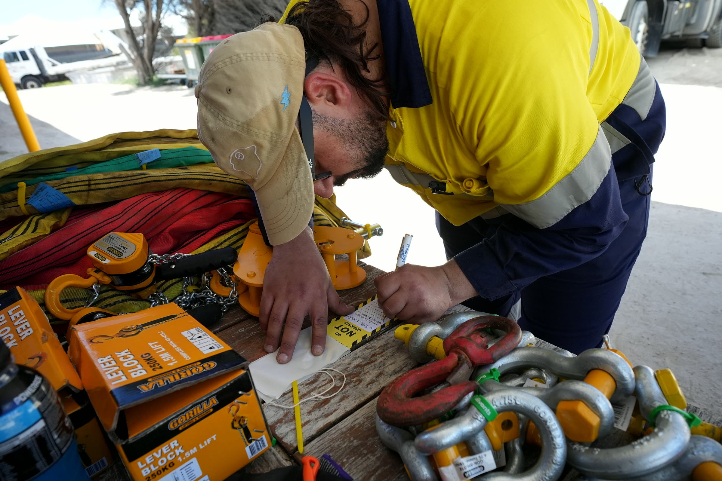 Writing an inspection tag at a bench of shackles, lever blocks and slings